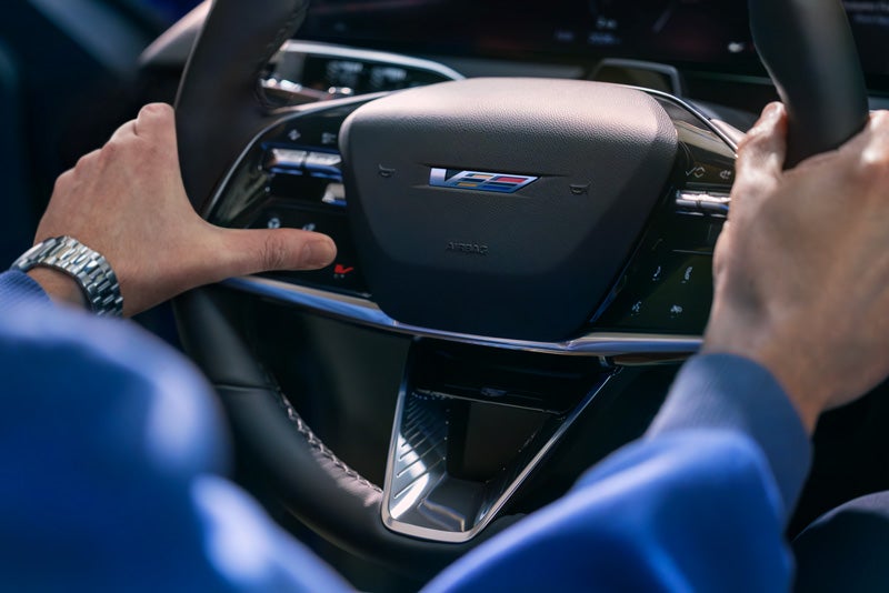 Close-up of a Man About to Press the V-Button on the 2026 OPTIQ-V Steering Wheel | Dan Vaden Chevrolet Brunswick in Brunswick GA